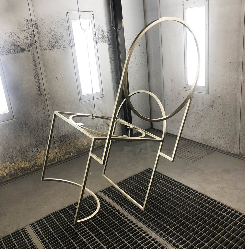 Minimal metal chair frame inside industrial powder coating workshop