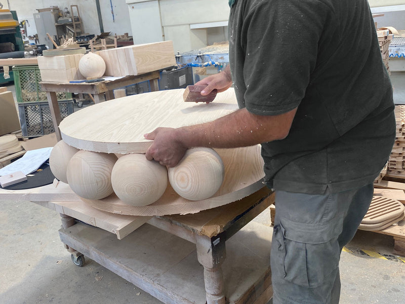 Craftsperson sanding handcrafted wooden furniture with spherical wood details
